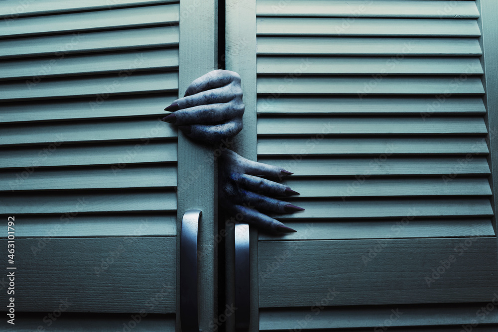 Horror blue toned cupboard or closet doors with scary female monster hands opening it. - obrazy, fototapety, plakaty 