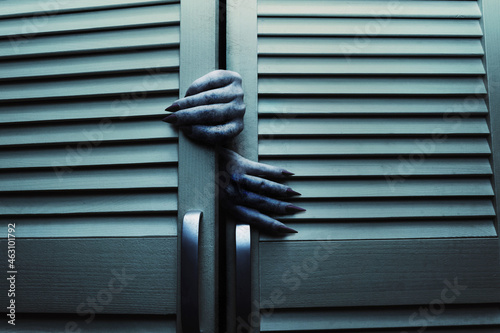 Horror blue toned cupboard or closet doors with scary female monster hands opening it. photo