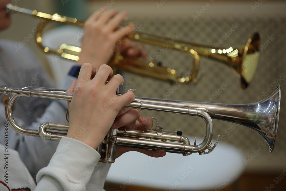 Obraz premium Playing the trumpet of two instruments gold and silver hands fingers close up musical background
