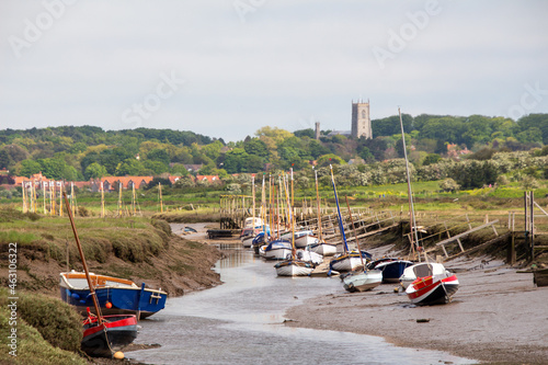 Boats stranded during low tide with Quay and Blakeney village and Church in the background North Norfolk, British Summer, low tide, boat on the shore photo