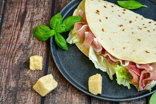 Italian Piadina Romagnola  with ham, mozzarella, rocked salad and tomatoes . Flatbread or open sandwich photo