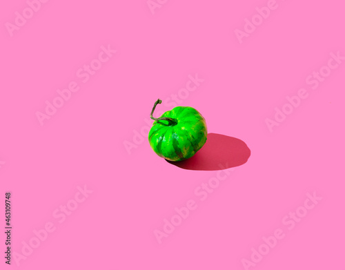 A bright green pumpkin on pink background. Happy clashy Halloween concept. photo