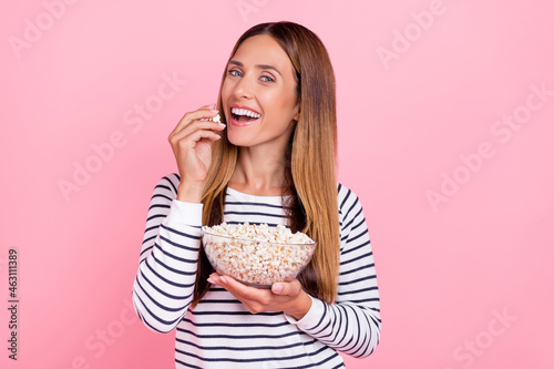 Photo of pretty charming mature lady wear striped sweater smiling eating popcorn isolated pink color background