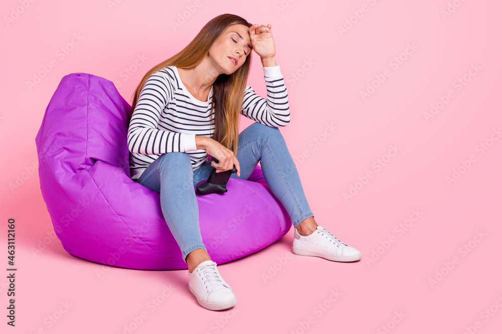 Full size photo of mature sad brown hairdo lady sit playstation wear shirt jeans shoes isolated on pink background - obrazy, fototapety, plakaty 