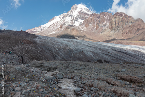 A cloudless view on Mount Kazbeg in Caucasus, Georgia. There slopes are barren and stony below the snow-capped peak and the Gergeti Glacier. Tranquillity. Natural remedy. Massive glacier foot © Chris