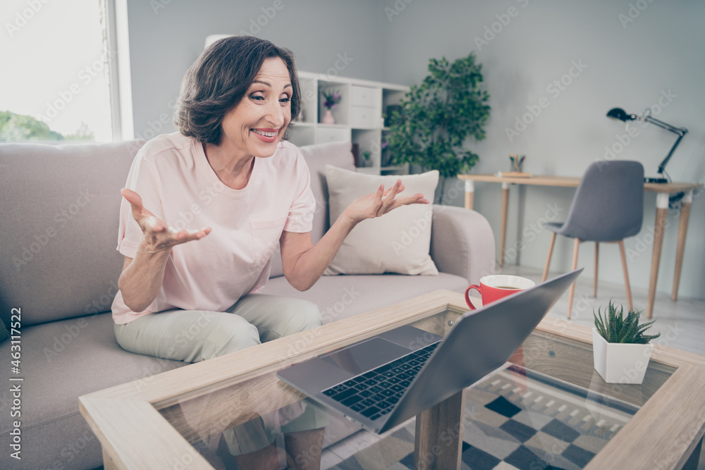 Photo portrait senior woman sitting on sofa working on computer talking on web camera online at home Photo portrait senior woman sitting on sofa working on computer talking on web camera online at home