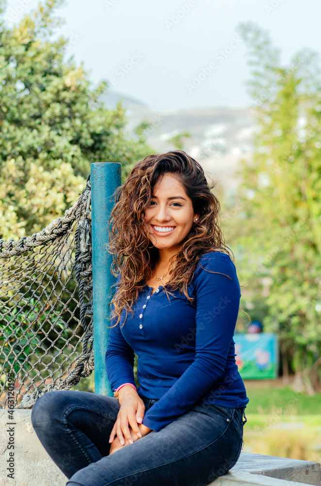 Obraz premium Beautiful young woman sitting on a stone bench in the park.