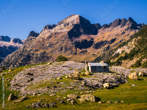 Paisje de alta montaña con un refugio de primer plano y altas montañs rocosas de fondo de pantalla con un cielo azul photo