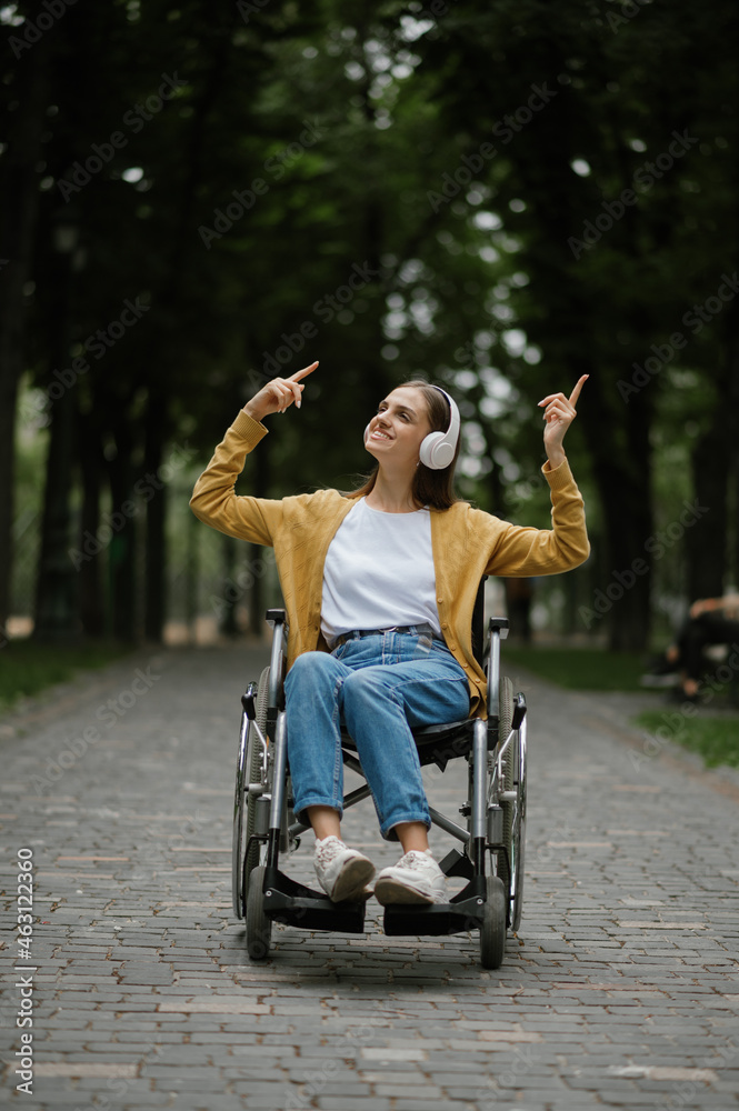 Disabled woman in wheelchair listens to music - obrazy, fototapety, plakaty 