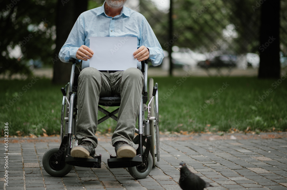 Adult disabled man in wheelchair walking in park - obrazy, fototapety, plakaty 