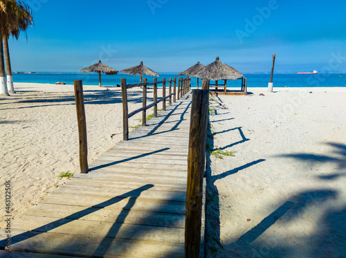 Wooden walkway on the beach with umbrellas in the background in Mexico