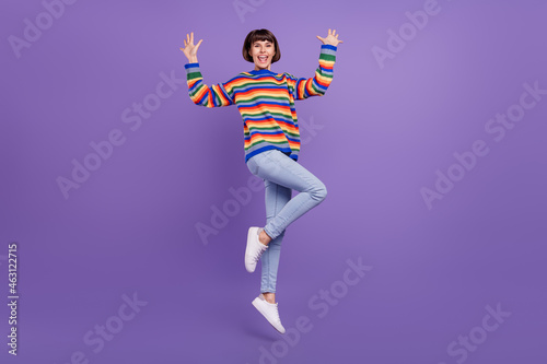 Photo of cheerful dream lady jump raise arms wear striped sweater jeans shoes isolated violet color background © deagreez