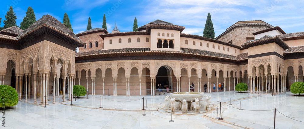 Full panoramic exterior view at the Patio at the Lions, twelve marble lions fountain on Palace of the Lions or Harem, Alhambra citadel, tourist people visiting