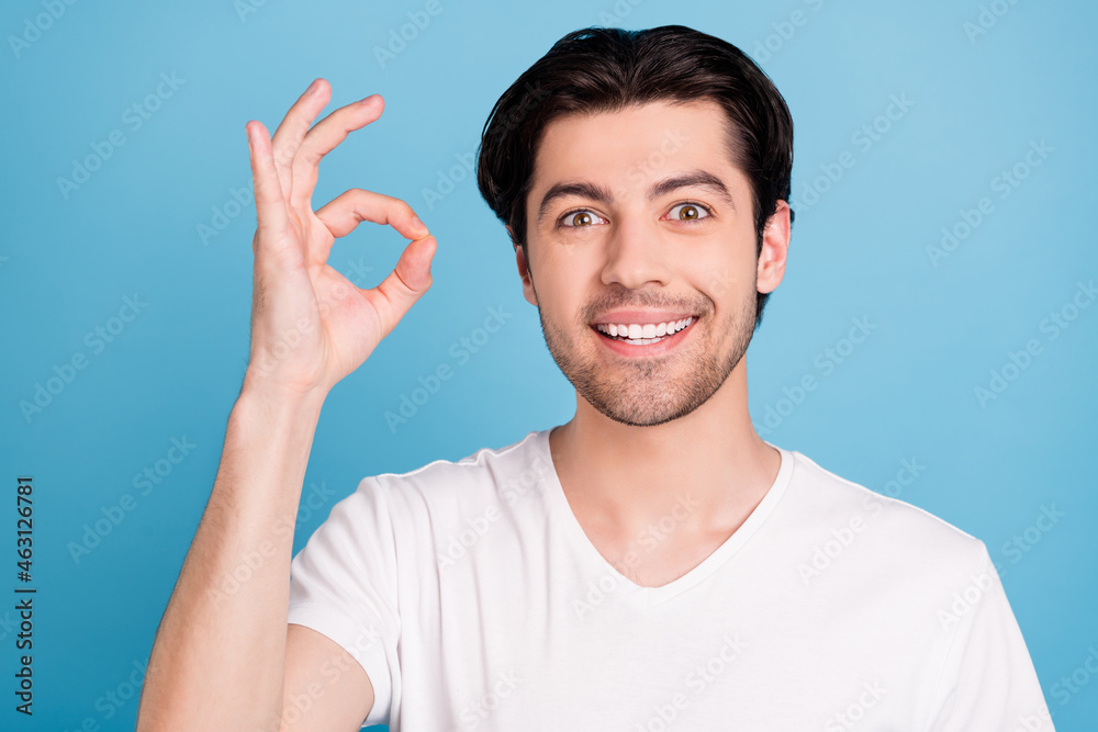 Photo of positive reliable guy show okey sign approve excellent choice wear white t-shirt isolated blue color background Photo of positive reliable guy show okey sign approve excellent choice wear white t-shirt isolated blue color background