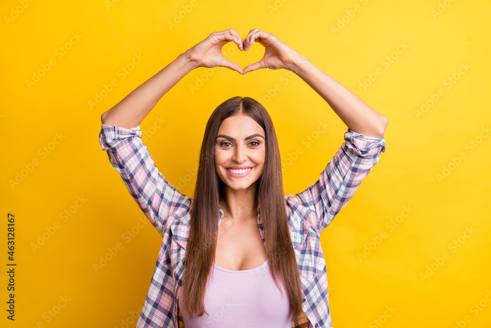 Photo of young woman happy positive smile show fingers heart figure romantic isolated over yellow color background Photo of young woman happy positive smile show fingers heart figure romantic isolated over yellow color background