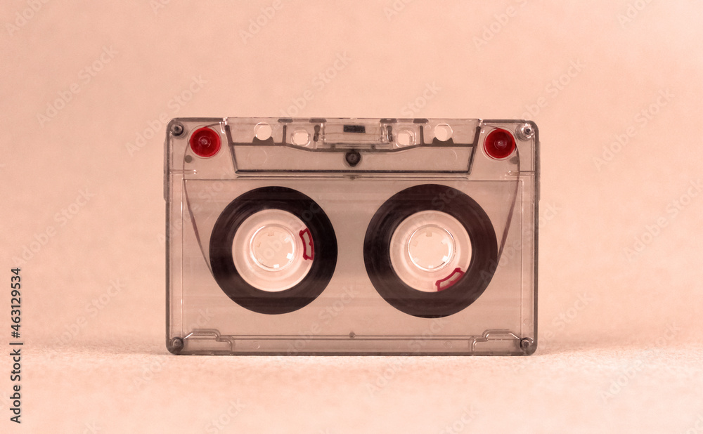 Fototapeta premium Retro audio cassette stands on a light background under orange lighting