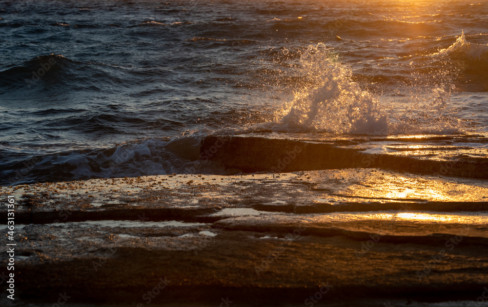 Stormy windy sea waves splashing on a rocky seashore at sunset Stormy windy sea waves splashing on a rocky seashore at sunset