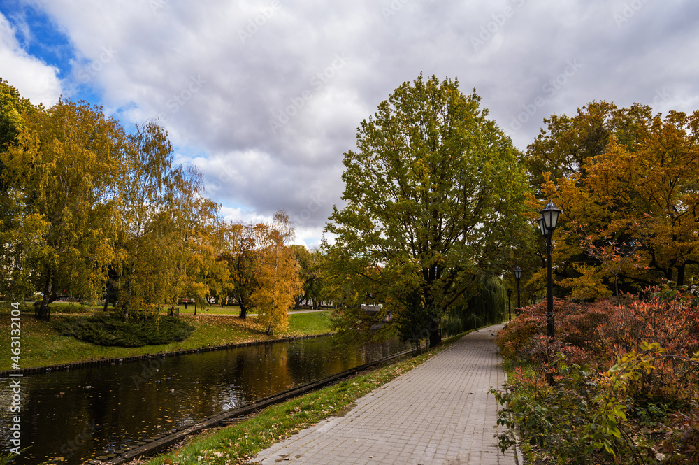 Autumn park with canal and pavement. Cloudy day. Riga, Latvia.