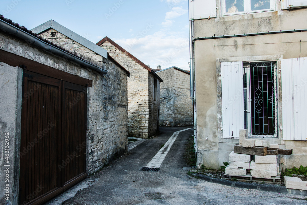 old, white barns near a house  in a street in the French village Arc-en-Barrois