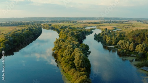 Aerial view above a beautiful landscape with a  river while sunset. Aerial view from drone flies over a beautiful summer landscape. © Valua Vitaly