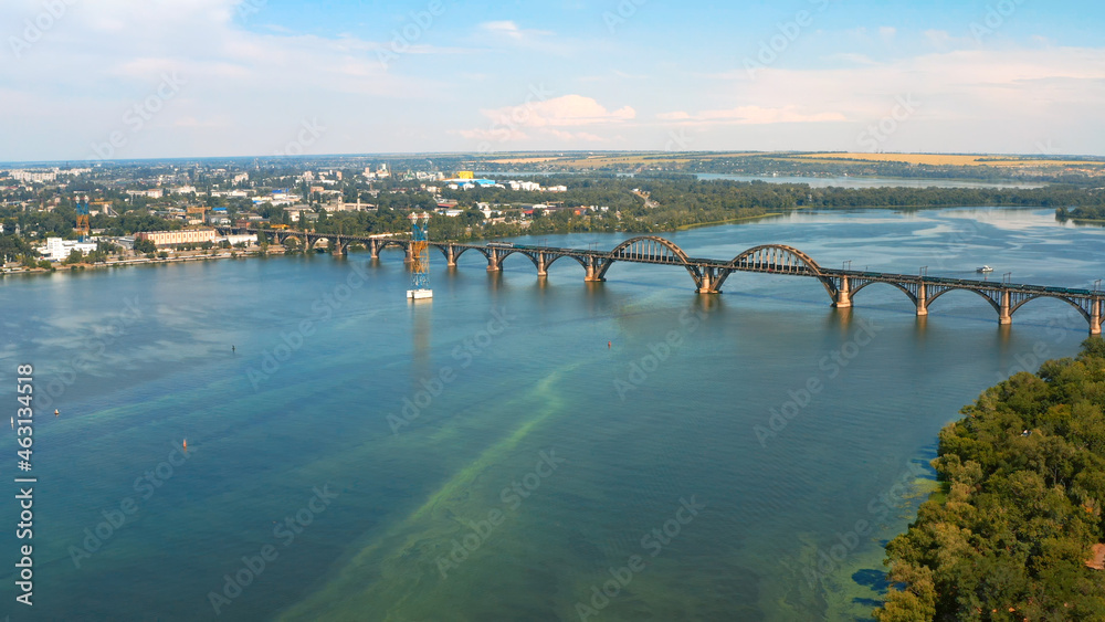 Aerial photo - Beautiful city landscape with a river. Photo of a beautiful long bridge over the river from the throne. Urban environment with a wide river.