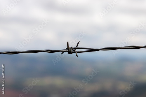 barbed wire fence with blurred nature background. selective focus