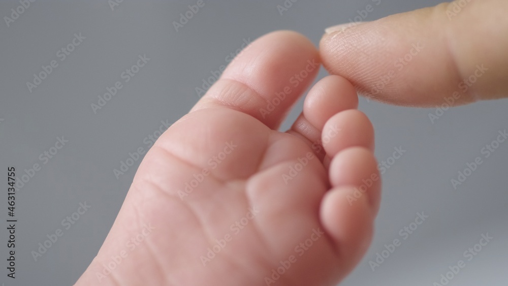Macro shot of infants toe. Mother touching her small child's toes while he is asleep. Mother touching her sons feet. Mum cares of her infant baby. Close up shot of loving mothers care. Macro shot of infants toe. Mother touching her small child's toes while he is asleep. Mother touching her sons feet. Mum cares of her infant baby. Close up shot of loving mothers care.