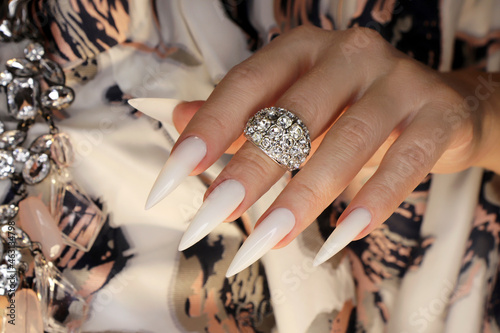 Long light manicure with jewelry on a woman's hand.