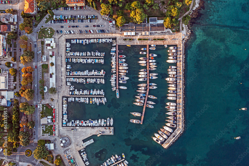 Obraz premium Vertical view of the harbor basin of the Croatian coastal town of Porec with yachts and fishing boats in the morning