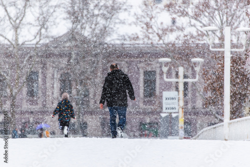Heavy snowfall in the city. Man and child walking in the snowy weather © eshana_blue