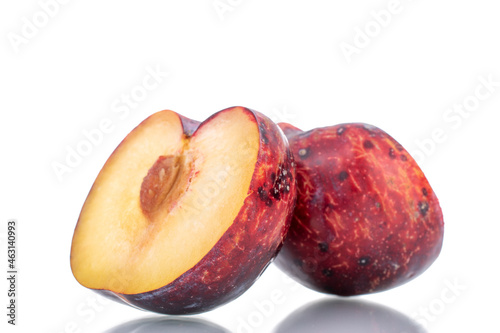 Two halves of a juicy purple plum, close-up, isolated on white.