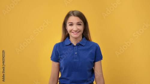 Portrait of cheerful young woman smiling with gesture come here asking joining to her posing isolated on orange studio
