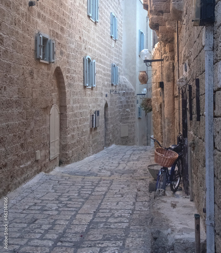 An old narrow street in old Jaffa paved with paving stones with houses with wall of large stones and arched openings
