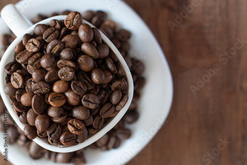 Coffee beans in white cup on brown wooden background