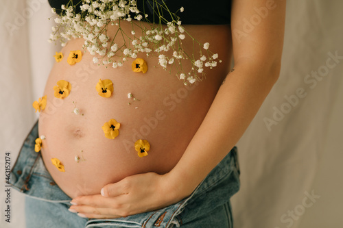 Crop of pregnant woman with flowers
 photo