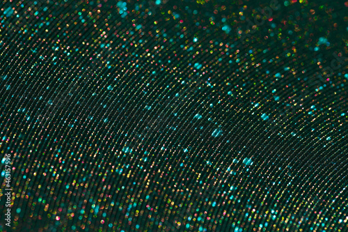 Wavy shimmering texture. Dark green background with graining and beautiful sequins close-up