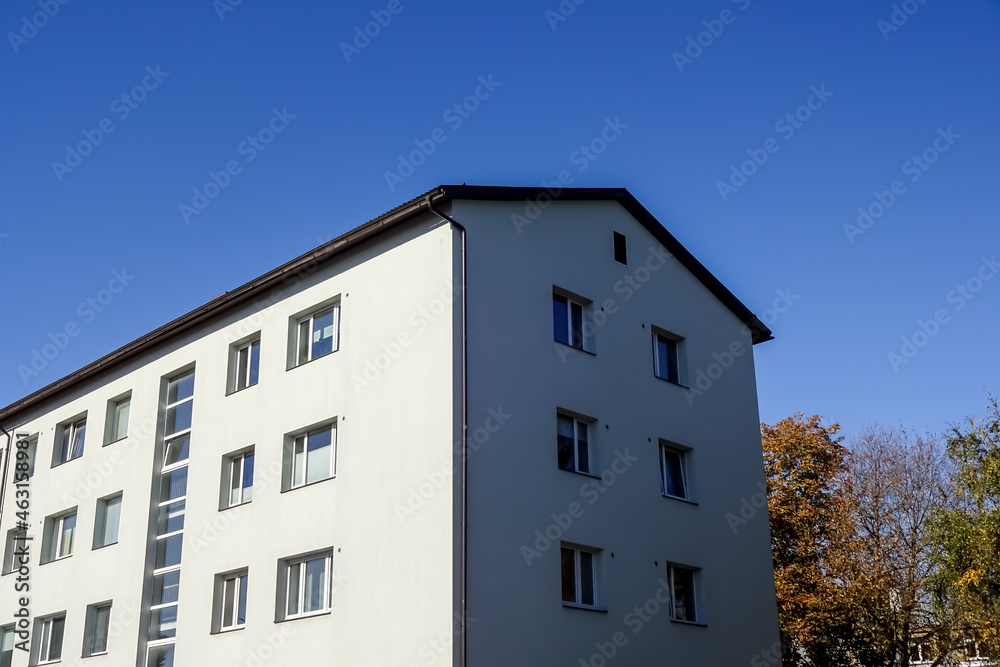 Close up of white house with clear blue sky background with an autumn foliage on the back. Bottom up view. Pelgulinna, Tallinn, Estonia, Europe. September 2021 Close up of white house with clear blue sky background with an autumn foliage on the back. Bottom up view. Pelgulinna, Tallinn, Estonia, Europe. September 2021