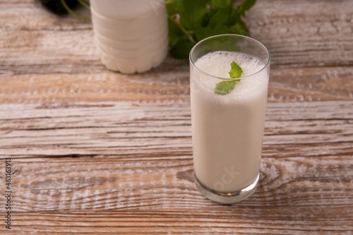 Turkish or Azerbaijan traditional Drink Ayran or Kefir with herbs and with mint in a glass on a wooden table front view. Fermented milk drink for diet. Copy space. the concept of healthy nutrition.