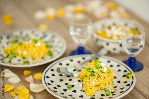 Yellow rice with greens on a cute plate with blue hearts and a table decorated with flower petals