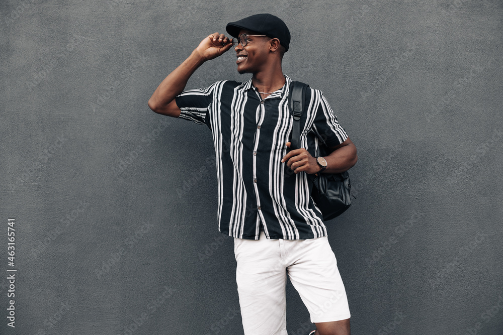 portrait of an African American man against a black wall, looking to the side, smiling broadly, wearing shirt and shert portrait of an African American man against a black wall, looking to the side, smiling broadly, wearing shirt and shert