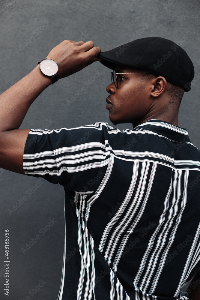 African american man holding a cap with his hand, fashion posing, pensive, fast-paced