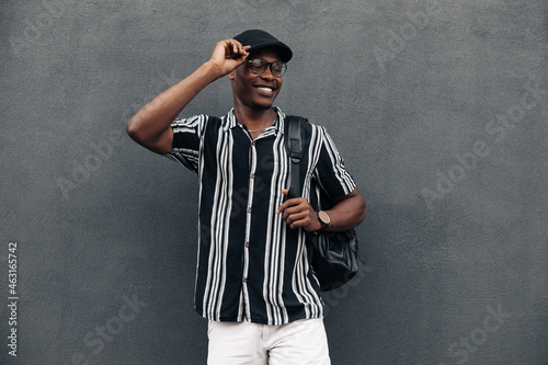 portrait of an African American man against a black wall, looking to the side, smiling broadly, wearing shirt and shert photo