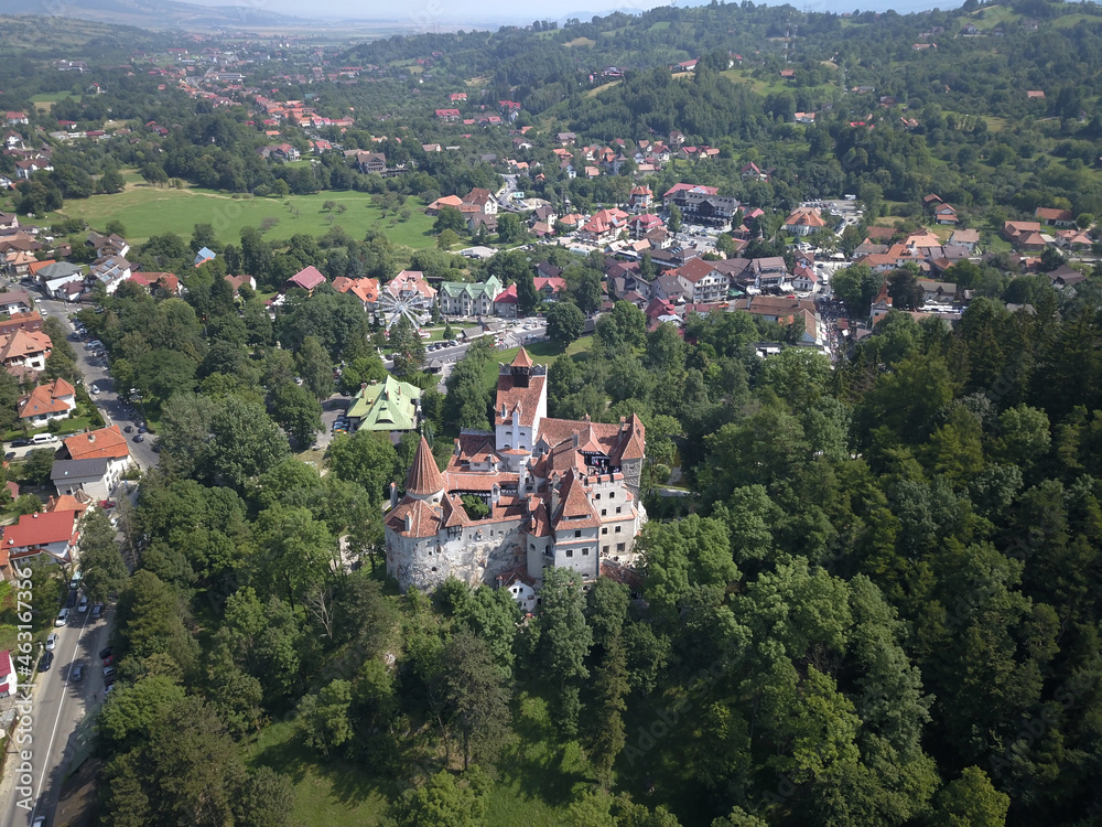 Aerial view of Bran Village and Bran castle in Transylvania, Romania with white houses, red roofs, green trees and blue sky