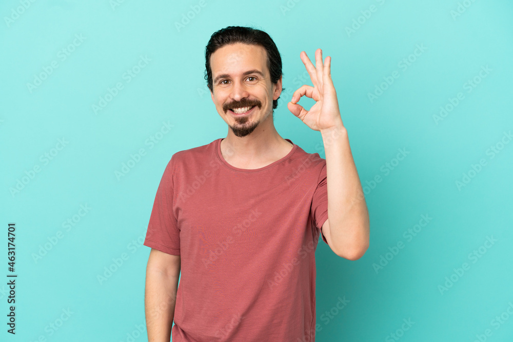 Young caucasian man isolated on blue background showing ok sign with fingers Young caucasian man isolated on blue background showing ok sign with fingers