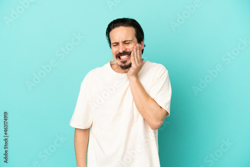 Young caucasian man isolated on blue background with toothache