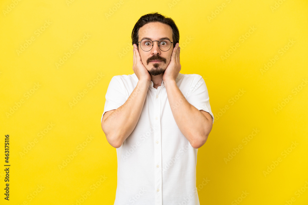 Young caucasian man isolated on yellow background frustrated and covering ears
