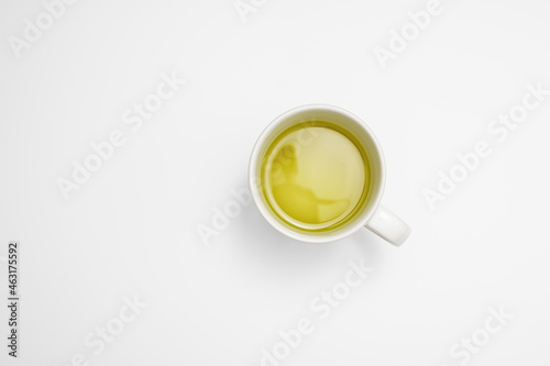 Taking a break: a large cup of green or herbal tea on a white desk surface. Minimalist table top view and copy space.