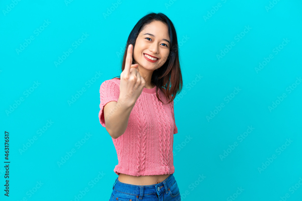 Young Vietnamese woman isolated on blue background doing coming gesture Young Vietnamese woman isolated on blue background doing coming gesture
