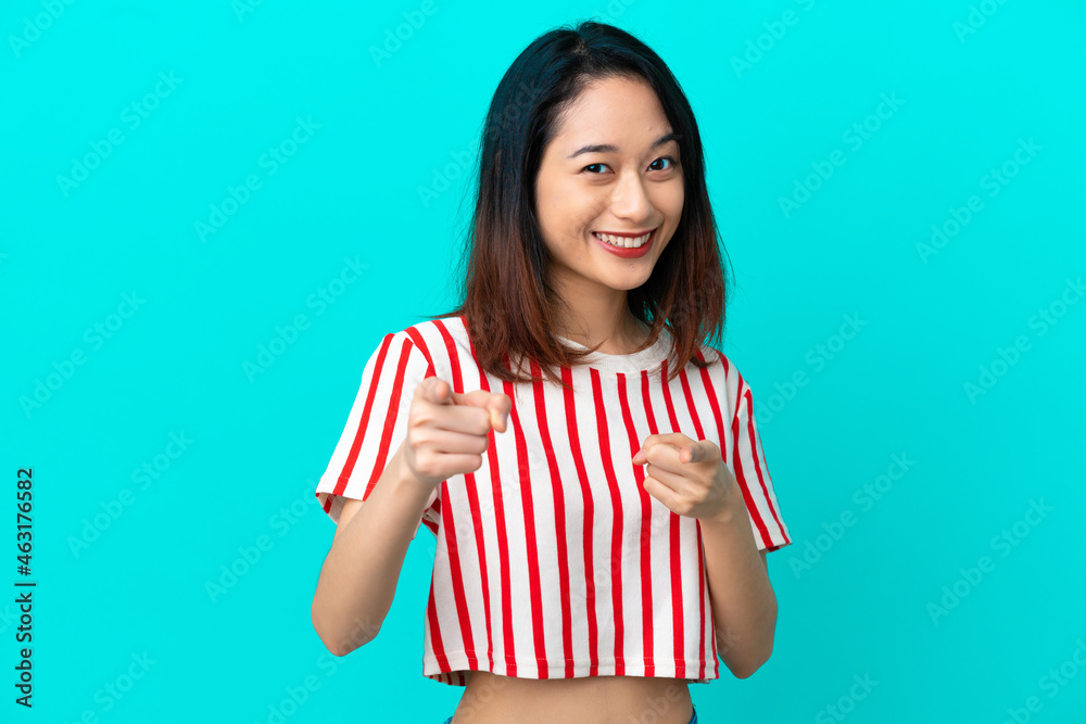 Young Vietnamese woman isolated on blue background pointing to the front and smiling Young Vietnamese woman isolated on blue background pointing to the front and smiling