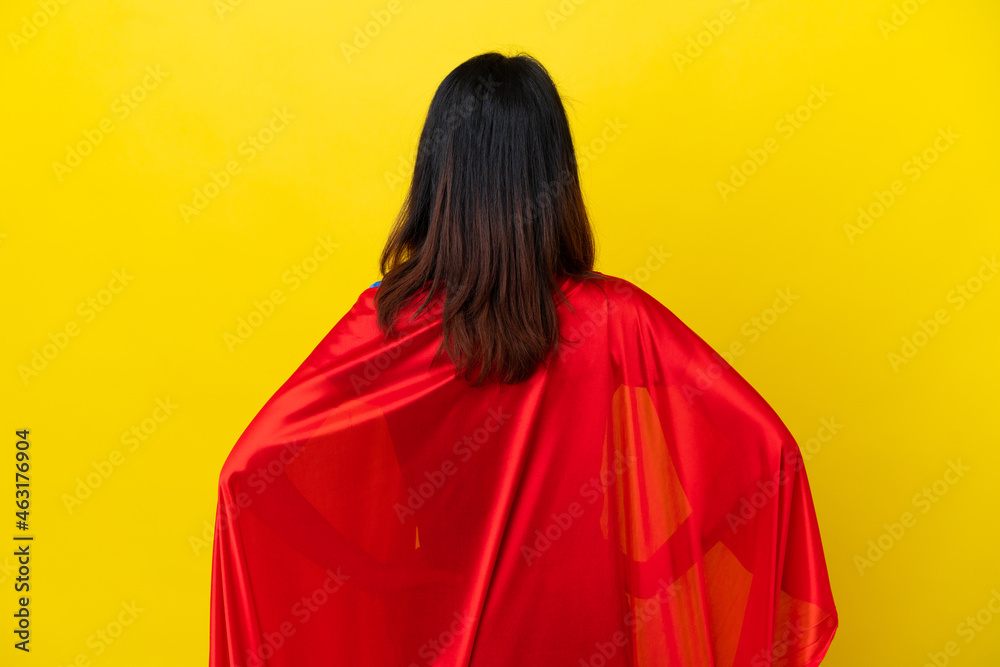 Super hero Vietnamese woman isolated on yellow background in back position Super hero Vietnamese woman isolated on yellow background in back position
